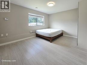 Burnaby apartment for rent - A bedroom with a bed, window, and wooden flooring.
