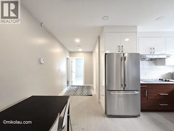 Burnaby apartment for rent - A modern kitchen with a stainless steel refrigerator and wooden flooring.