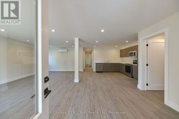 Orillia triplex for rent - A spacious living room with a kitchen area in the background.