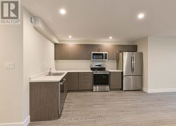 Orillia triplex for rent - A kitchen with a refrigerator, oven, and microwave.