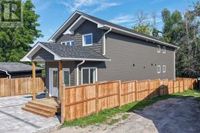 Orillia triplex for rent - A grey house with a wooden fence and a grey roof.