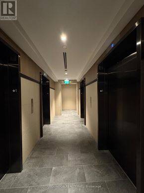 Toronto (Church-Yonge Corridor) condo for rent - A long hallway with elevators on both sides and a green exit sign above.