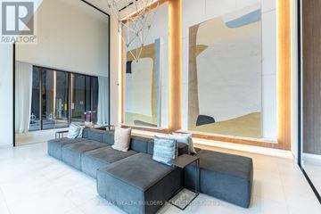 Toronto (Waterfront Communities) condo for rent - A modern living room with a large grey sofa and a large abstract painting on the wall.