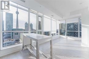 Toronto (Waterfront Communities) condo for rent - A spacious room with a large table and a view of the city skyline through the windows.