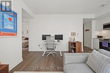Toronto (Waterfront Communities) condo for rent - A modern living room with a grey couch and a white desk with a computer.