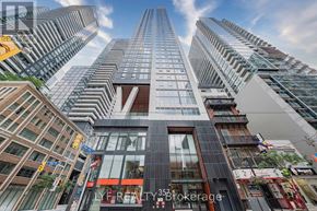 Toronto (Waterfront Communities) condo for rent - A tall building with a glass facade stands in front of other buildings.