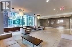 Toronto (Moss Park) condo for rent - A modern waiting area with a glass wall and a brown table.