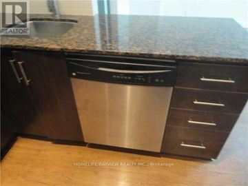 Toronto (Moss Park) condo for rent - A stainless steel dishwasher is installed in a kitchen with wooden cabinets.