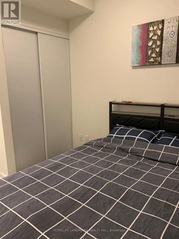 Toronto (Waterfront Communities) condo for rent - A bedroom with a bed and a painting on the wall.