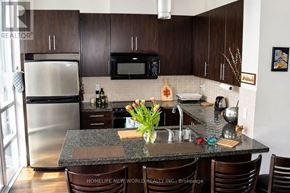 Toronto (North St. James Town) condo for rent - A kitchen with a granite counter top and brown chairs.