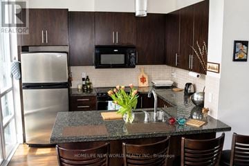 Toronto (North St. James Town) condo for rent - A kitchen with a granite counter top and brown chairs.