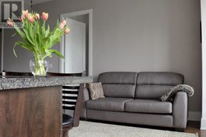 Toronto (North St. James Town) condo for rent - A grey couch with a glass vase of pink flowers on a wooden table.