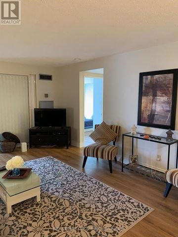 Toronto (Steeles) condo for rent - A living room with a glass coffee table and a striped chair.