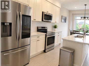 Brantford apartment for rent - A kitchen with a stainless steel refrigerator and white cabinets.