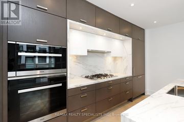 Toronto (Waterfront Communities) condo for rent - A modern kitchen with dark brown cabinets and a marble backsplash.