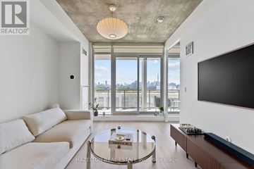 Toronto (Little Portugal) condo for rent - A living room with a white couch and a flat screen TV mounted on the wall.
