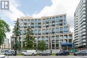 Toronto (Edenbridge-Humber Valley) condo for rent - A modern multi-story building with a parking lot in front.