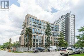 Toronto (Edenbridge-Humber Valley) condo for rent - A modern multi-story building with a parking lot in front.