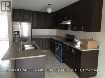 Brampton (Sandringham-Wellington North) townhouse for rent - A kitchen with dark brown cabinets and a granite countertop.