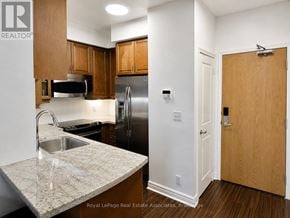 Toronto (South Parkdale) condo for rent - A kitchen with a sink, refrigerator, and cabinets.