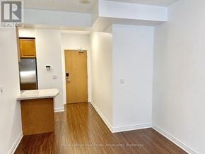 Toronto (South Parkdale) condo for rent - A white hallway with a wooden door and a counter.