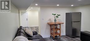 Toronto (Weston-Pellam Park) apartment for rent - A living room with a couch, a table, and a refrigerator.