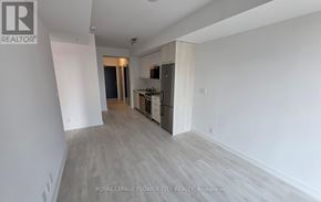 Hamilton (Corktown) condo for rent - A spacious room with a kitchen area in the background.