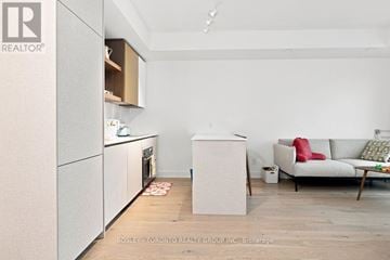 Toronto (Greenwood-Coxwell) condo for rent - A kitchen with a refrigerator, oven, and a couch in the living room.