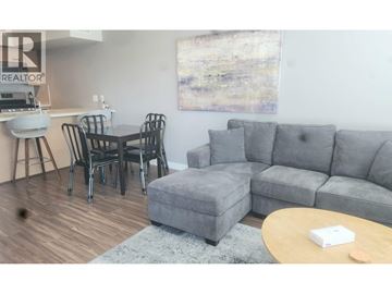 Richmond apartment for rent - A living room with a grey couch, a coffee table, and a dining table with chairs.