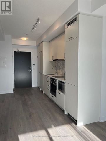 Vaughan (Vaughan Corporate Centre) condo for rent - A modern kitchen with white cabinets and a black door.