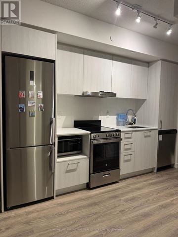 Vaughan (Vaughan Corporate Centre) condo for rent - A modern kitchen with a stainless steel refrigerator and wooden flooring.