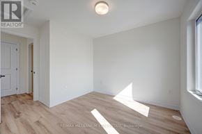 Brampton (Northwest Brampton) townhouse for rent - A room with white walls and wooden flooring, with a door on the left and a window on the right.