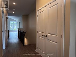 Brockville apartment for rent - A hallway with a white door and a window in the distance.