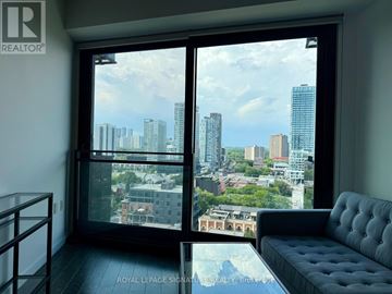 Toronto (Moss Park) condo for rent - A living room with a couch and a view of the city through a large window.