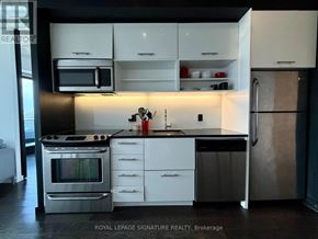 Toronto (Moss Park) condo for rent - A modern kitchen with white cabinets and stainless steel appliances.