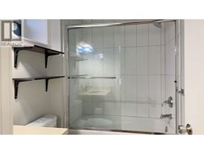 Burnaby apartment for rent - A glass shower stall with a glass door and a white toilet in the corner.