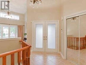 Brampton (Bramalea North Industrial) apartment for rent - A room with a chandelier, a window with curtains, a wooden railing, a glass door, and a plant on a table.