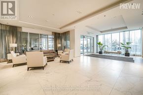 Toronto (South Parkdale) condo for rent - A spacious living room with a large window and a view of the trees outside.