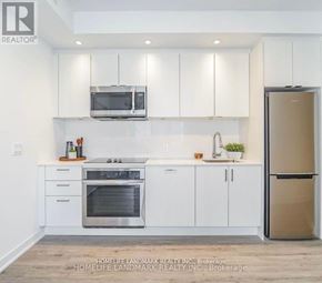 Toronto (South Parkdale) condo for rent - A modern kitchen with white cabinets and stainless steel appliances.