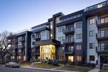 Calgary apartment for rent - A modern apartment building with balconies and a car parked in front.