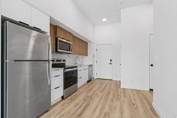 Calgary apartment for rent - A modern kitchen with a stainless steel refrigerator and wooden cabinets.
