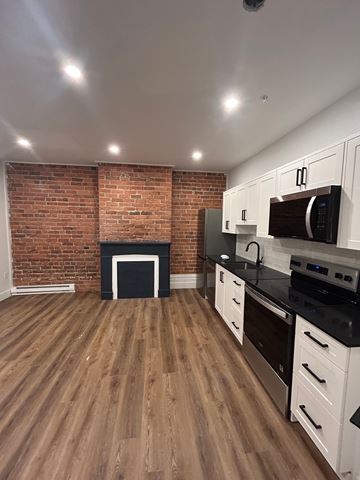 Halifax apartment for rent - A kitchen with a brick wall and wooden floors.