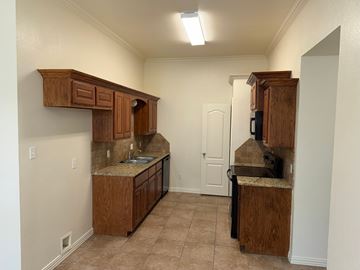 Temple triplex for rent - A kitchen with wooden cabinets and a countertop.