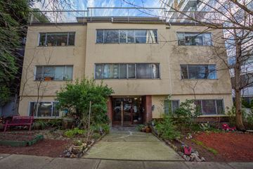Vancouver apartment for rent - A beige building with a red bench in front of it.