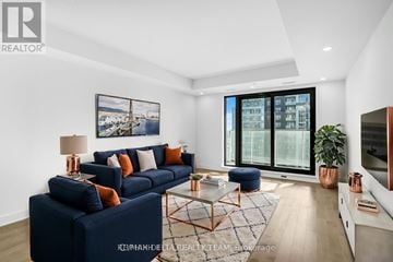 Ottawa condo for rent - A living room with a blue sofa and a large window.