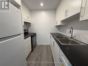 Ottawa townhouse for rent - A kitchen with white cabinets and a black countertop.