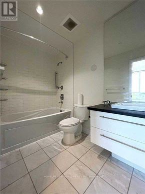 Toronto (Willowdale East) condo for rent - A white toilet in a bathroom with a black counter top.