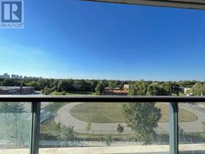 Toronto (Willowdale East) condo for rent - A view from a balcony overlooking a roundabout with a building and trees in the distance.