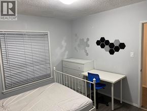 Vancouver apartment for rent - A bedroom with a bed, desk, and window with blinds.
