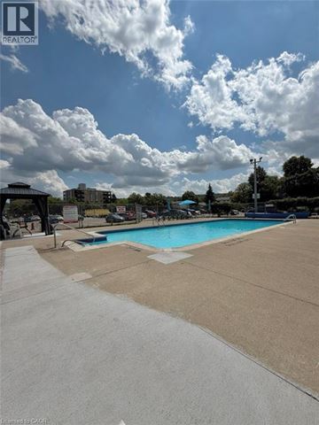 Hamilton condo for rent - A swimming pool surrounded by a concrete deck and a cloudy sky.